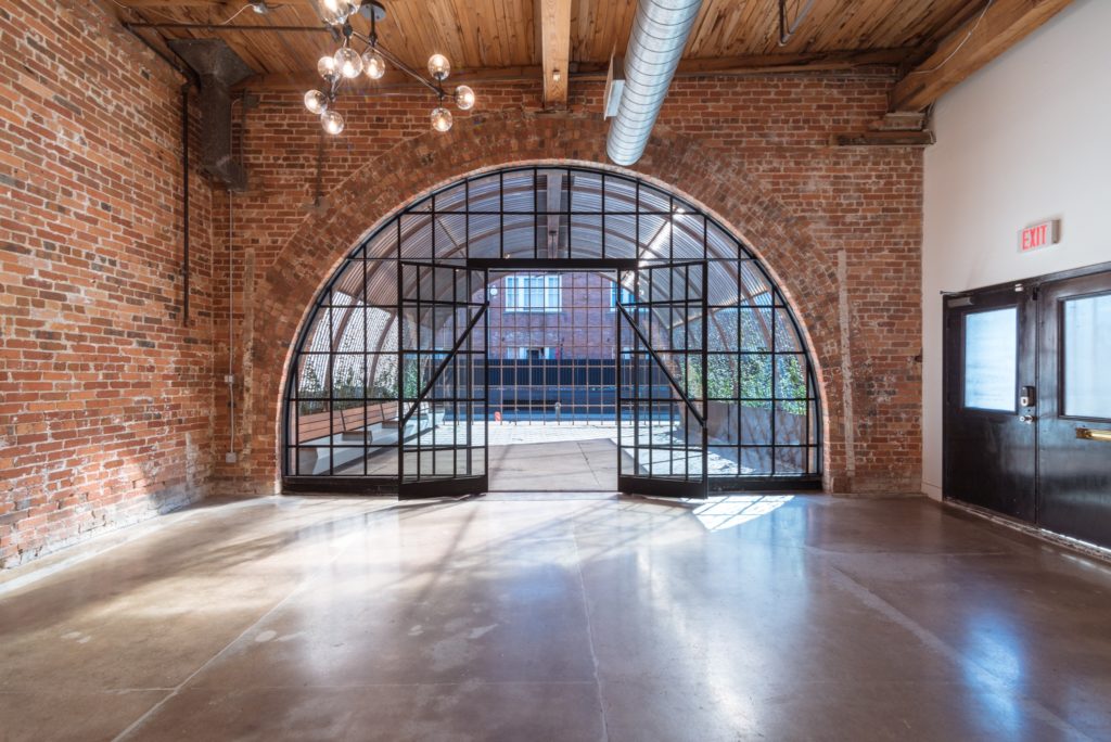 Glass arch entrance surrounded by brick accent wall interior at Ronin Art House 2