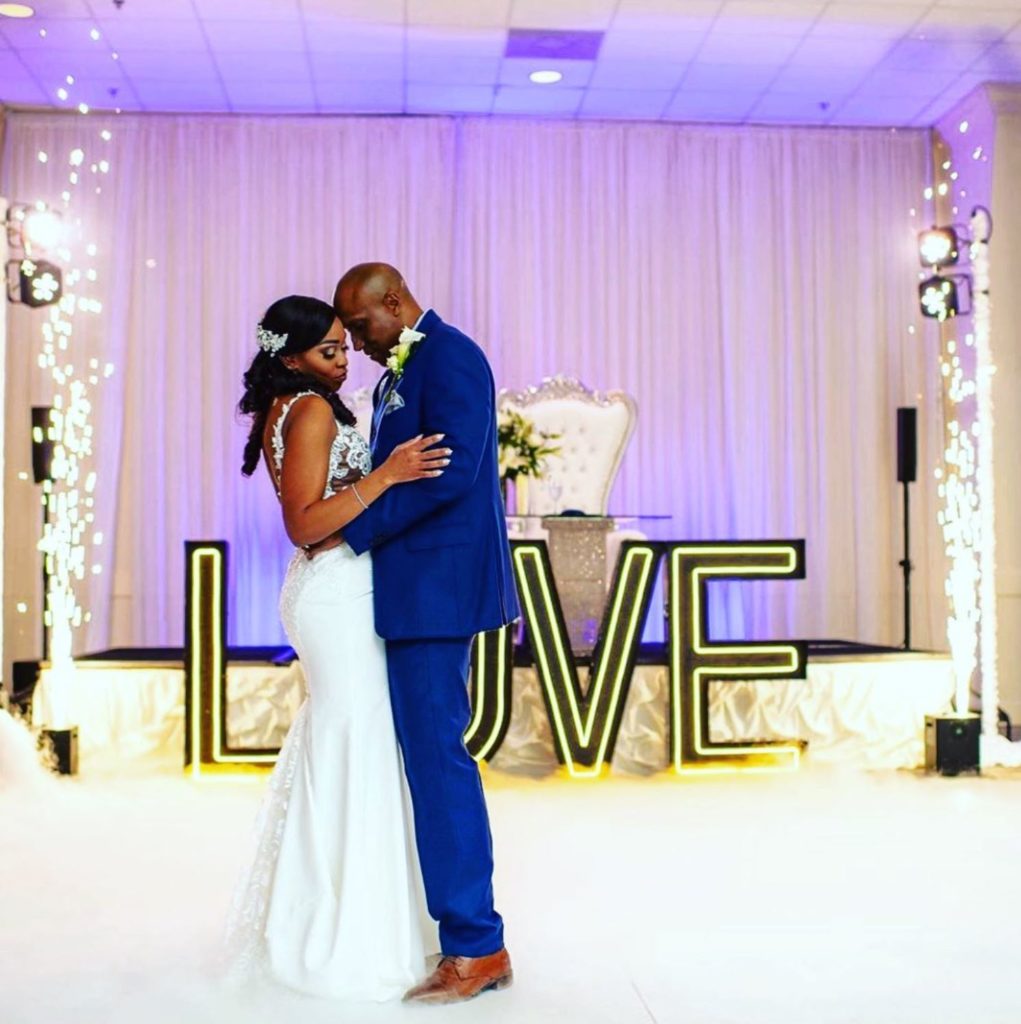 Black bride and groom dance at Signature Manor in front of marquee spelling Love 