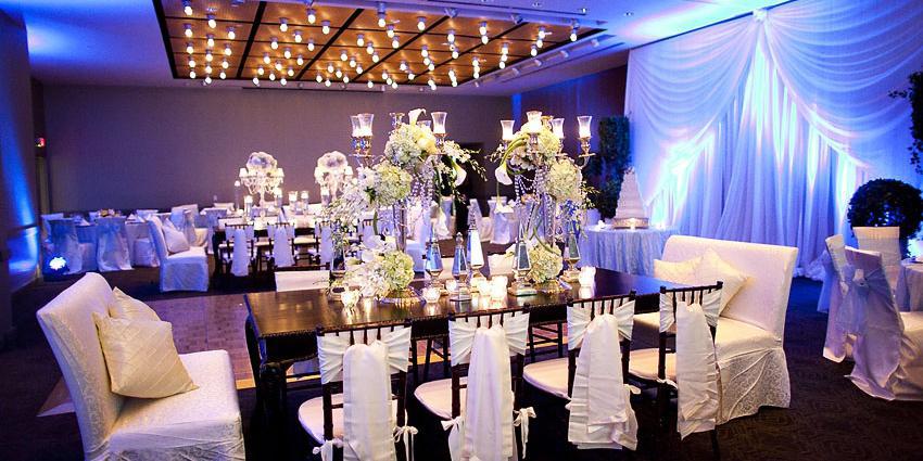 Rectangular tables for eight set for a wedding and decorated with tall floral centerpieces. 