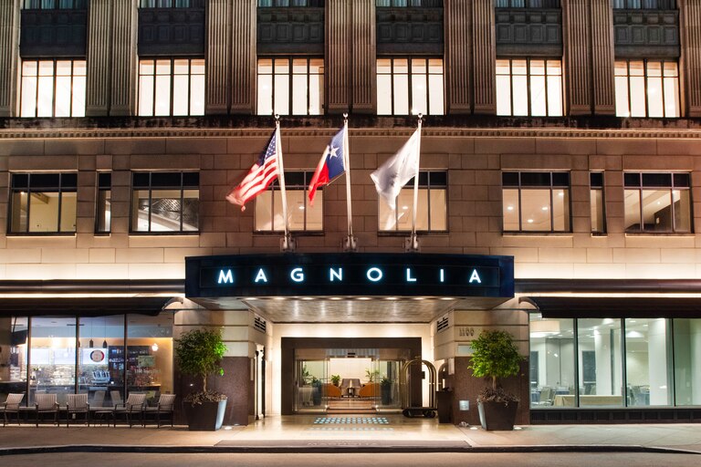 Exterior view of Magnolia Hotel in Houston with flags flying above the marquee sign