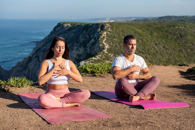 A couple sitting on mats outside doing yoga