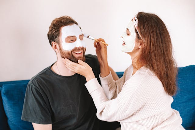 A woman putting a face mask on a man